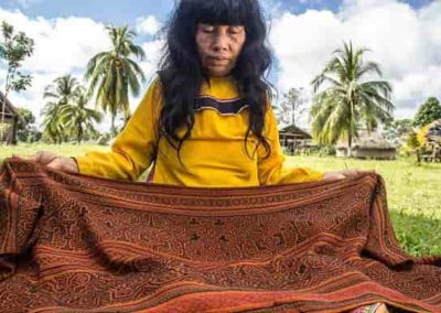 Mujer nativa mostrando un manto tejido, parte de su Artesanía y folklore